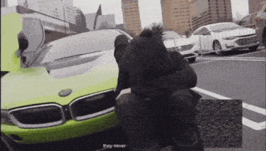 a man sits in front of a green bmw with the words they never on the bottom