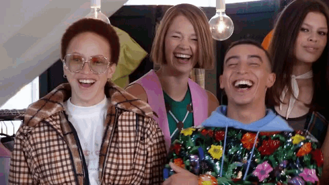 a group of people are laughing together and one of them is wearing a floral jacket