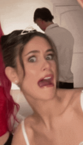 a woman is making a funny face with a man in the background .