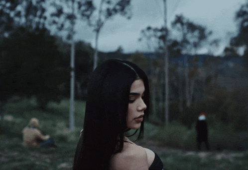 a woman in a black off the shoulder top stands in a field