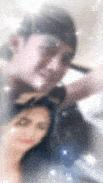 a blurry picture of a man and a woman with the letter m on the bottom left