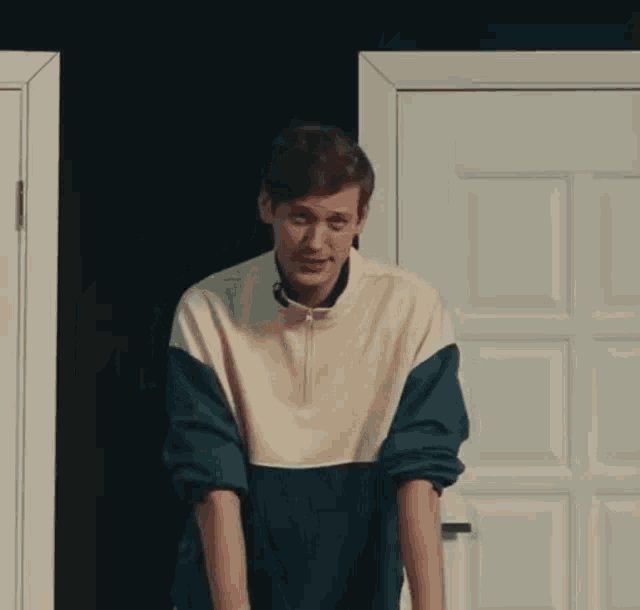 a young man is standing in front of a door and making a face .