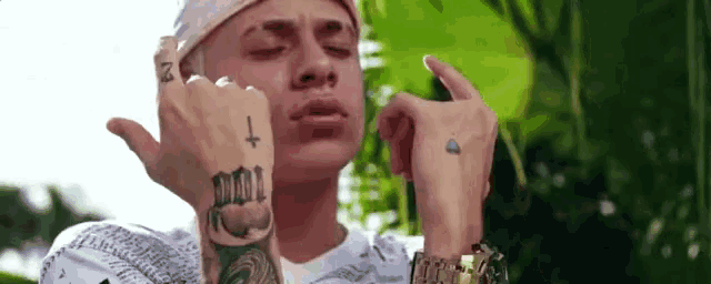 a man with a tattoo on his hand is giving the middle finger .