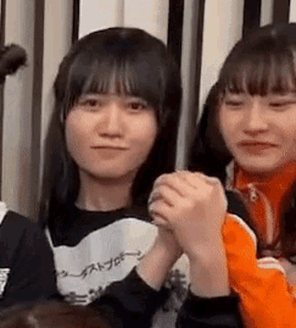 a group of young women are holding hands and smiling .