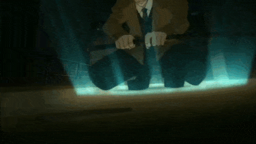 a man in a suit and tie is kneeling down in a dark room