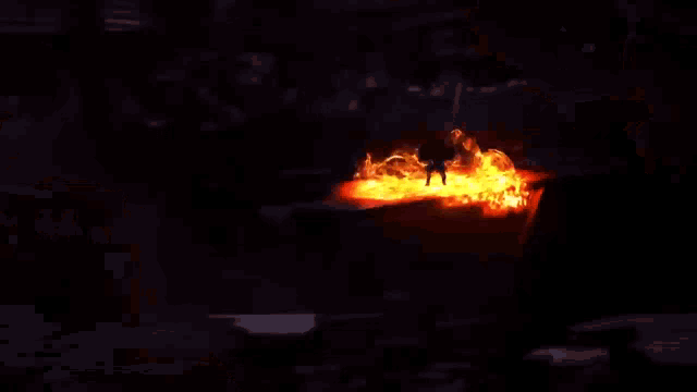 a man with a sword is standing in front of a wall of fire .