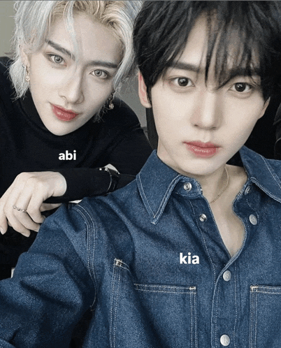 two young men are posing for a picture and one of them is wearing a denim shirt with the word kia on it