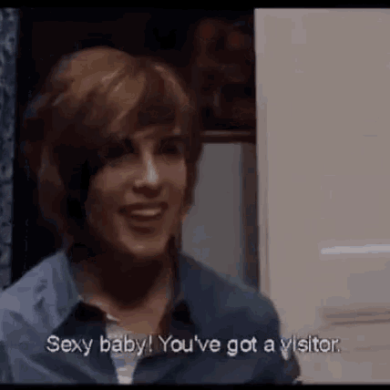 a woman in a blue shirt is smiling and saying sexy baby you 've got a visitor