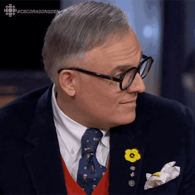 a man in a suit and tie with a yellow flower pin on his pocket square