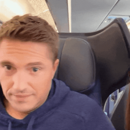 a man in a blue hoodie is sitting in a plane