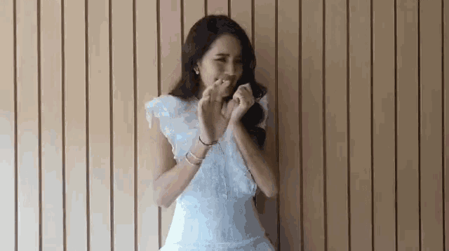 a woman in a white dress is making a heart with her hands .