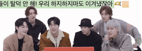 a group of young men are sitting around a laptop with korean writing on the bottom right