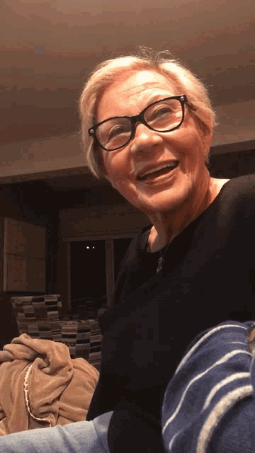 an older woman wearing glasses and a black shirt smiles