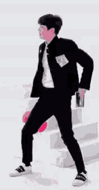a man in a black jacket and pants is standing on a white surface .