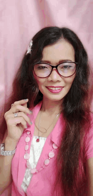a woman wearing glasses and a pink shirt is smiling