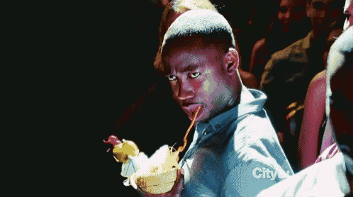 a man is drinking from a coconut with a straw while a crowd watches