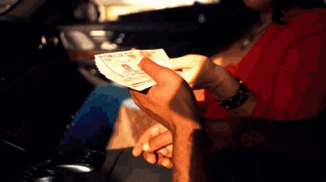 a woman in a red shirt is holding a stack of money in her hands