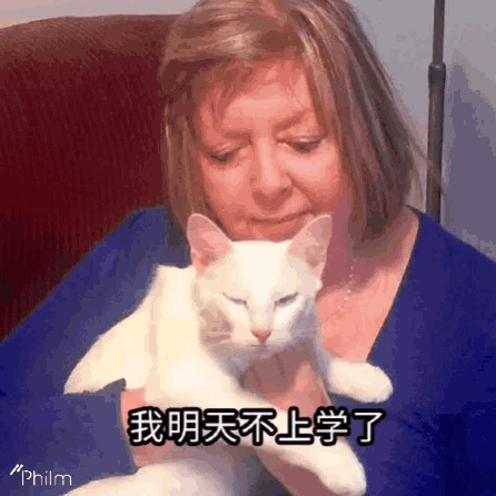 a woman in a blue shirt is holding a white cat with chinese writing on it .