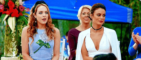 three women are standing next to each other in front of a blue canopy .