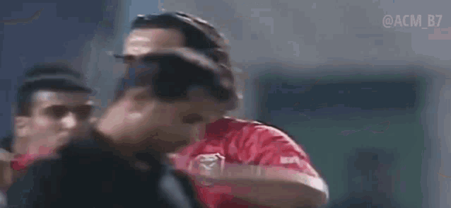 a soccer player wearing a red jersey with the number 8 on it is standing in front of a group of people .