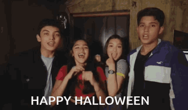 a group of young people are posing for a picture with the words happy halloween behind them .