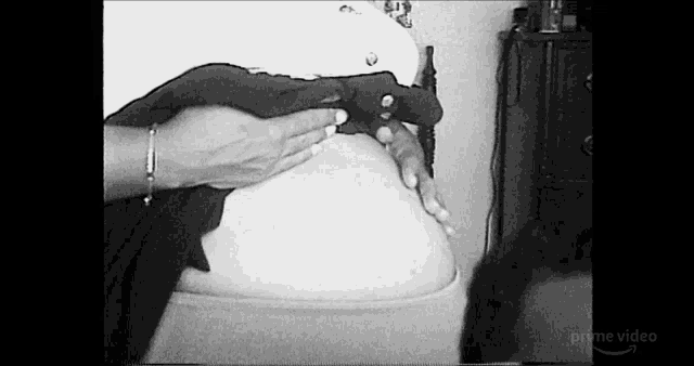 a woman is holding her pregnant belly in a black and white photo .