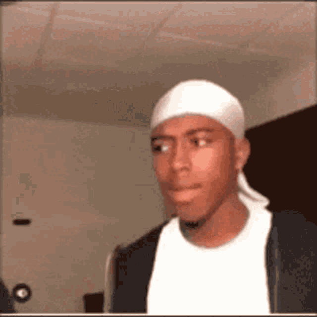 a man wearing a white headband and a black jacket is making a funny face .