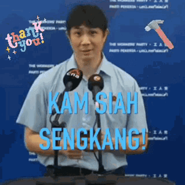 a man stands at a podium with microphones and says kam siah sengkang
