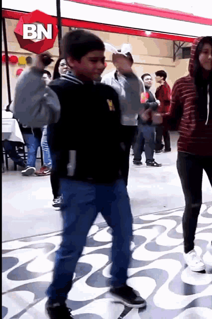 a boy dancing in front of a bn sign