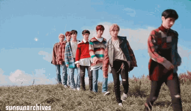 a group of young men are walking on a grassy hill with sunsunarchives written on the bottom