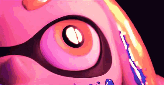 a close up of a pink squid 's eye with a blue squid in it 's mouth .