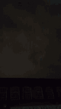 a black background with a blurred image of a person standing in the dark .
