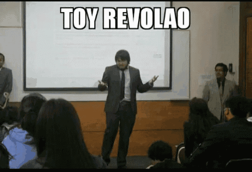 a man in a suit and tie is giving a presentation in front of a projector screen that says toy revolao on it