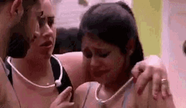 a man is comforting a woman who is crying while another woman looks on .