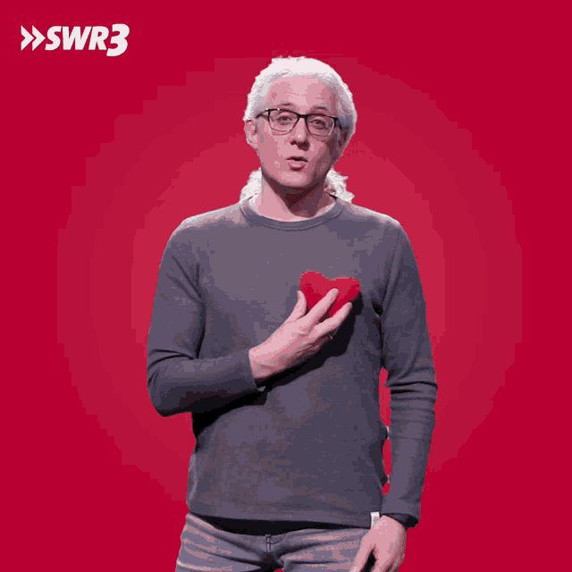 a man holding a red heart in front of a red background with the letters swr3