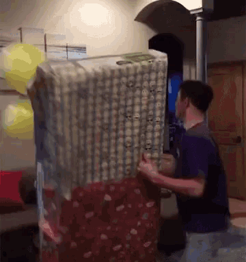 a man in a purple shirt is carrying a large box of money