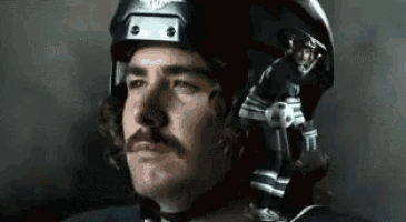 a man with a mustache is wearing a helmet and holding a soccer ball .