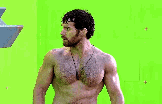 a shirtless man standing in front of a green screen .