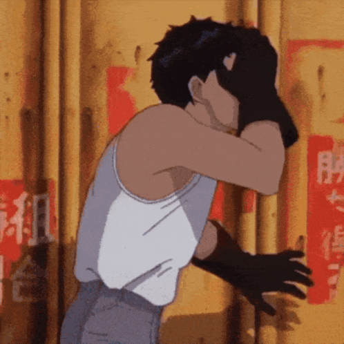 a man in a white tank top is covering his face with his hand
