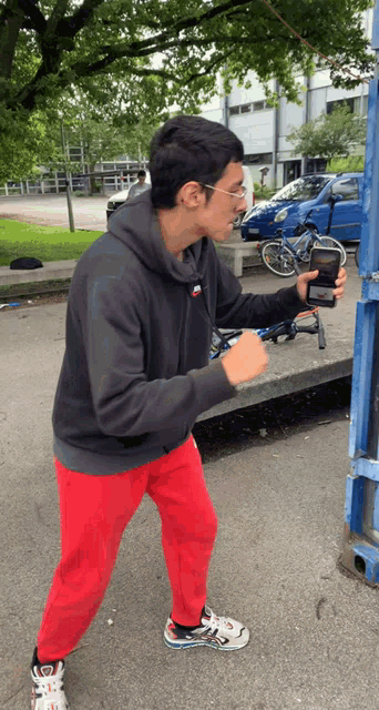 a man in a nike hoodie is holding a cell phone in his hand
