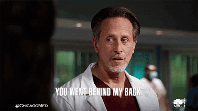 a man in a lab coat is talking to a woman and says " you went behind my back "