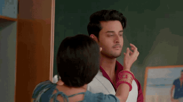 a woman is touching a man 's face in a room