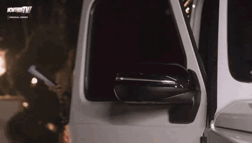 a white jeep is parked on the side of the road at night with its door open .