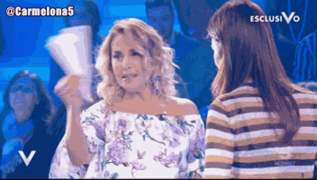 a woman in a floral top is talking to another woman on a tv show