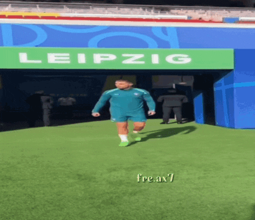 a man is running on a field in front of a leipzig sign