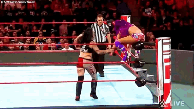 two women are wrestling in a ring with a referee watching .