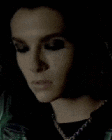a close up of a woman 's face with green hair and black eye shadow .
