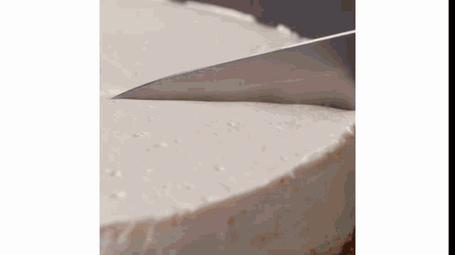 a close up of a person cutting a piece of cheesecake with a knife .