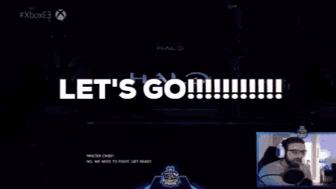 a screen says let 's go while a man stands in front of a microphone