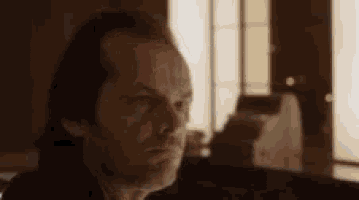 a close up of a man 's face in a room with a window in the background .